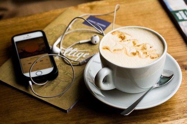 Image shows phone, coffee and headphones on a table, ready to listen to a funny book on Audible