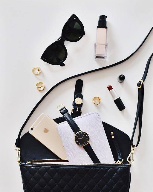 Image shows items fallng out of a handbag including a watch, perfume and sunglasses.