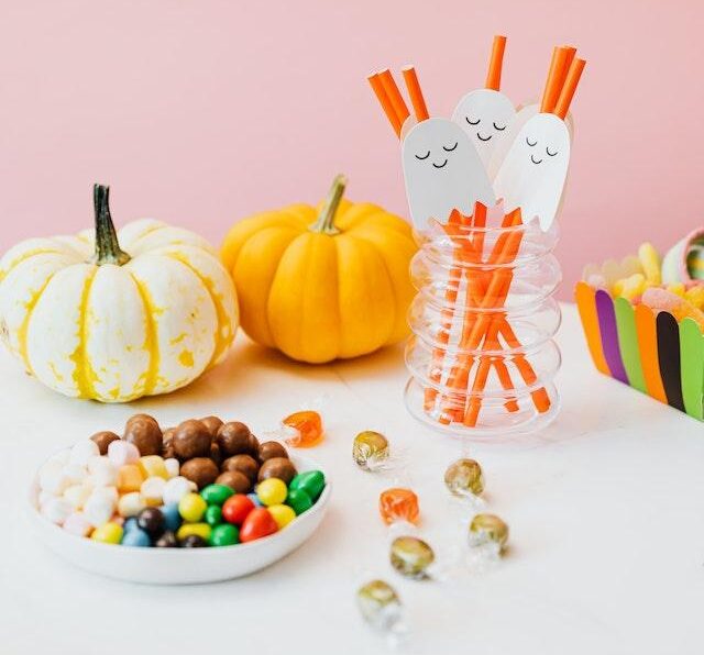 Image shows a simple table set up with two pumkins, ghost straws and some sweets for the blog How to Have a Hassle-Free Halloween