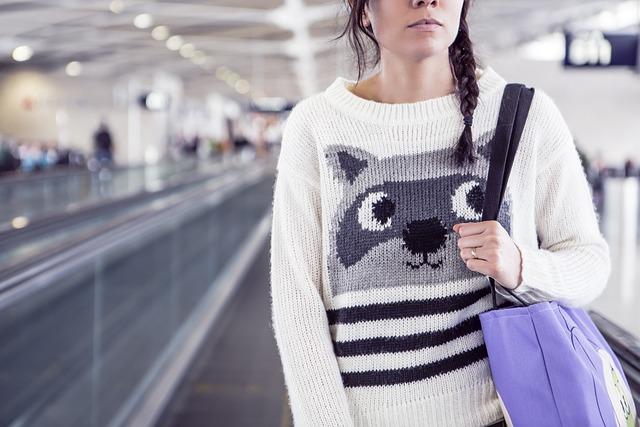 Image shows a woman in a comfy sweater with a racoon print on the front as part of the blog on Long-Haul Flight Tips for Ultimate Comfort, Rest, and Entertainment