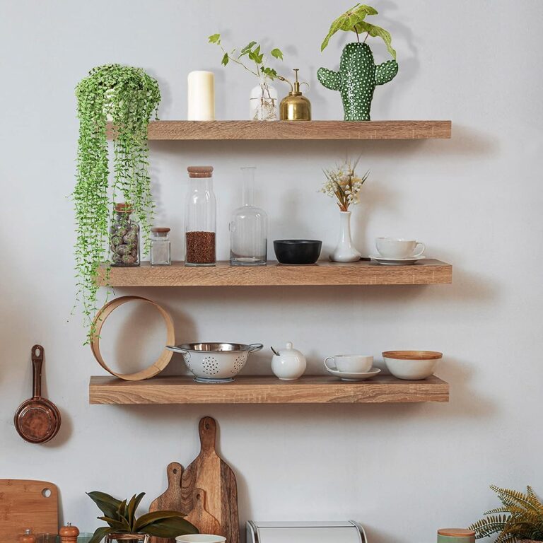 Image shows wall mounted floating shelves with kitchen products and plants on them, as part of a blog on mastering home organisation.