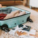 Image shows a mint hardshell suitcase open on a soft rug with two items thrown into the case.