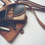 Image shows essential items for handbag including a purse, pen and glasses.